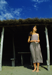 chris garner in front of hut, blue sky background, fashion photo by Steve Landis