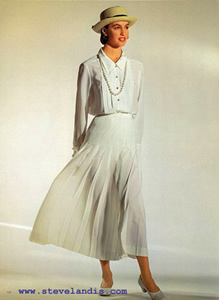 model in white pleated skirt which is blowing in the wind and white long sleeve shirt with smallish straw hat from Chanel, with beautiful light