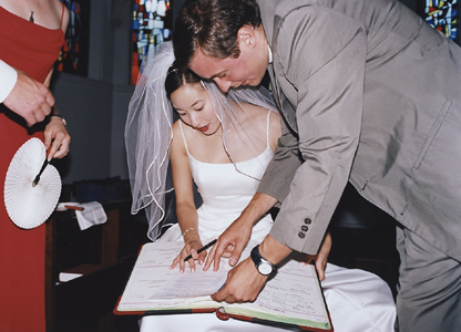 bride signs wedding documents with clergy